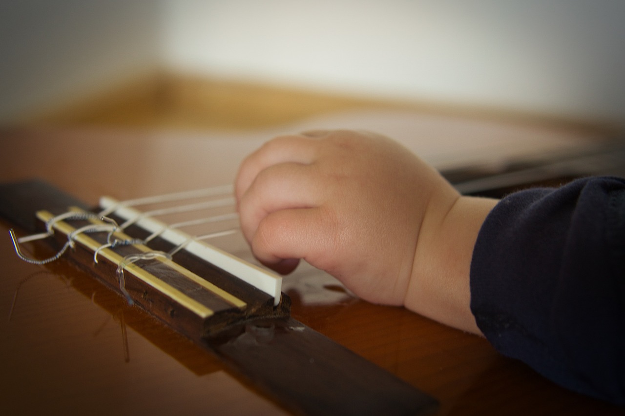 Main d'un jeune enfant sur une guitare